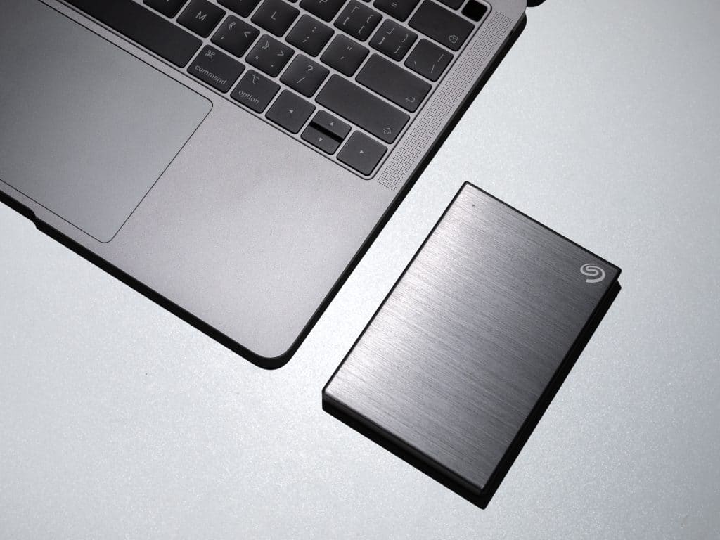 Metade de um notebook e o melhor HD externo em cima de uma mesa.