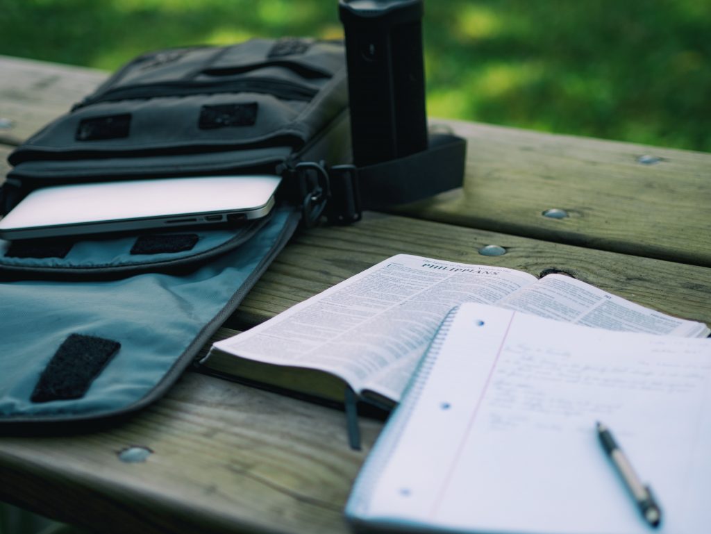 A melhor mochila para notebook ao lado de um livro e um caderno