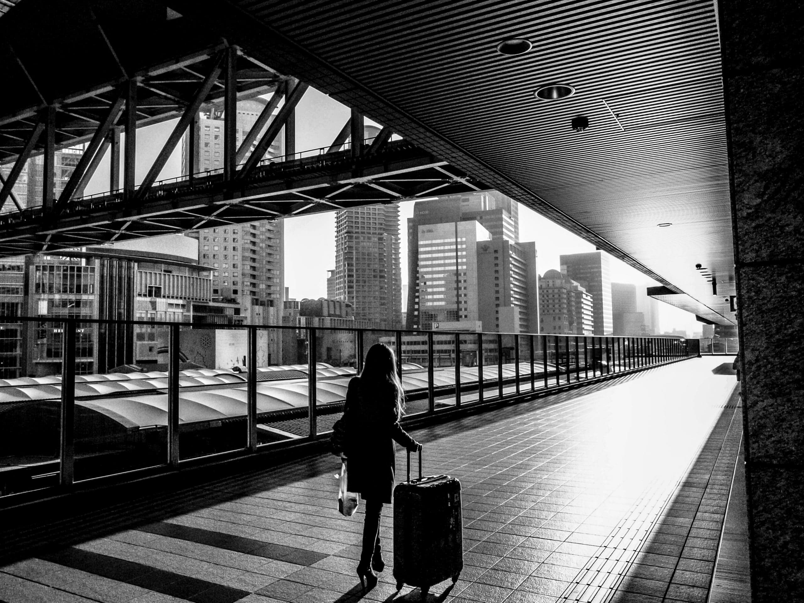 Imagem em preto e branco de mulher carregando a melhor mala de viagem