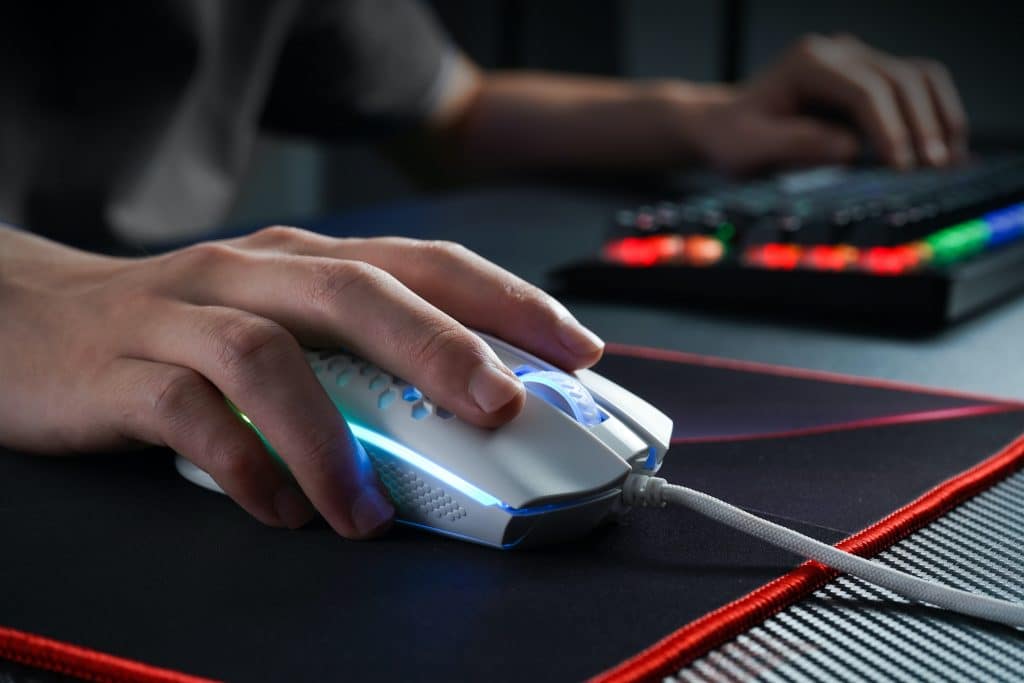 Mão segurando um mouse em cima do melhor mouse pad gamer