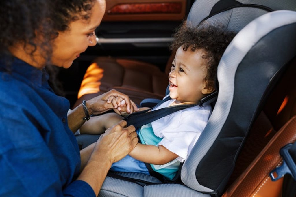 Mulher segurando as mães de criança sentada na melhor cadeirinha para auto.