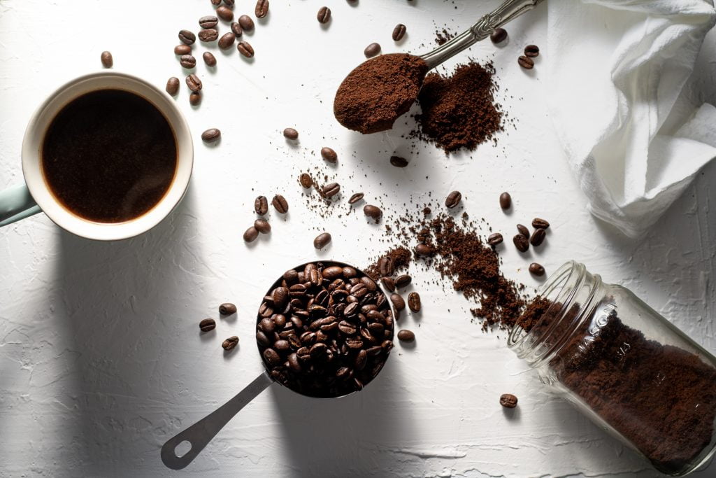 Café coado, grãos de café e café moído  sobre um fundo branco.
