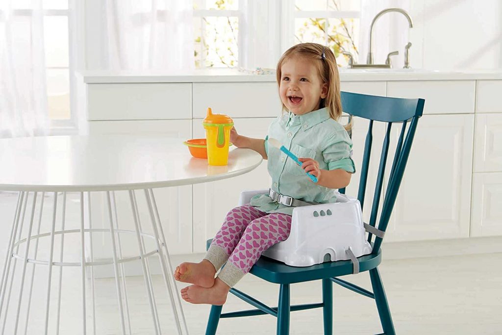 Criança sentada à mesa com a melhor cadeira de alimentação portátil