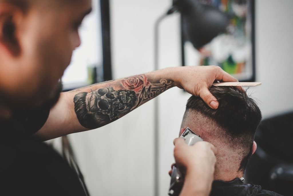 Barbeiro usando a melhor máquina de cortar cabelo em seu cliente.