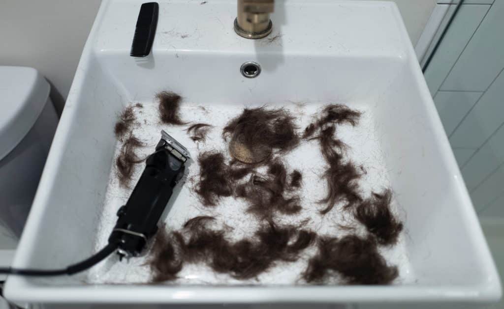 A melhor máquina de cortar cabelo dentro de uma pia branca e cheia de cabelo cortado