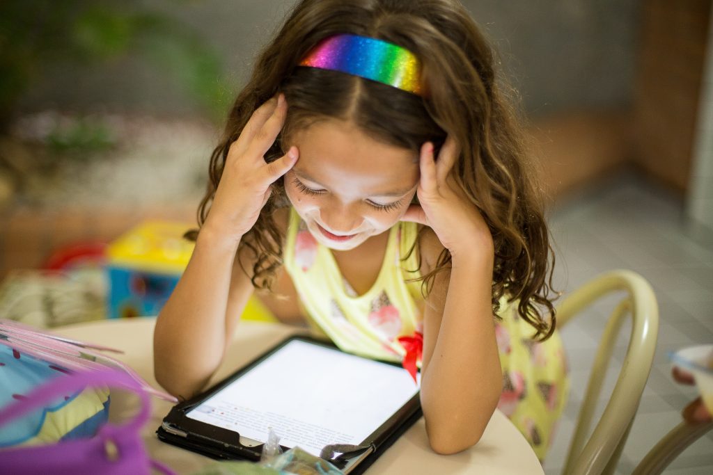 Menina usando o melhor tablet infantil em cima da mesa. 