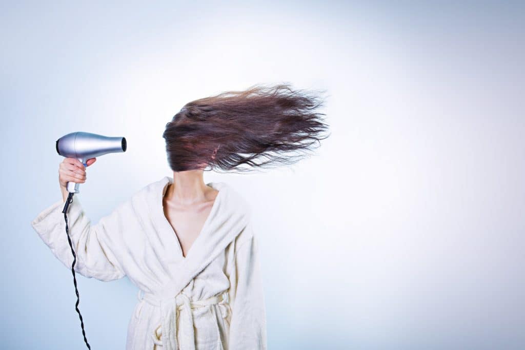 Mulher segurando o melhor secador de cabelo e os cabelos voando para o lado.