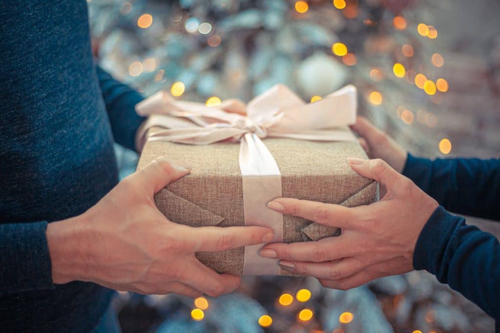 Mãos segurando uma caixa com os melhores presentes de Natal para homens.