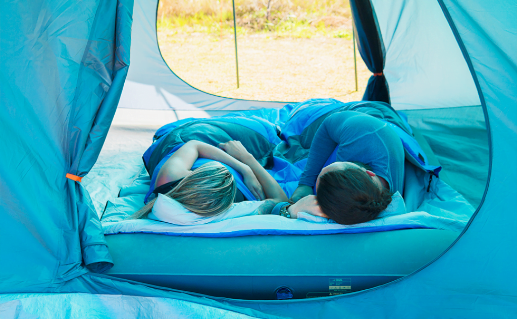 Casal dormindo no melhor colchão inflável dentro de uma barraca de acampamento. 