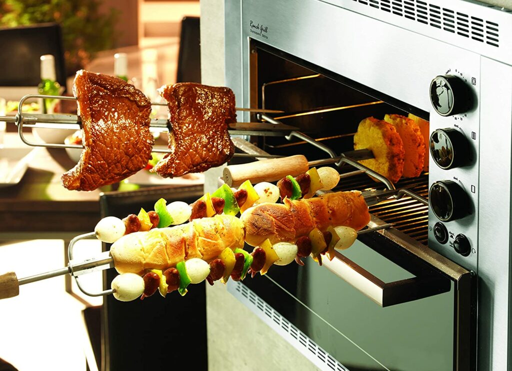 Espetos de carne e pão de alho sendo colocados na melhor churrasqueira elétrica de embutir.