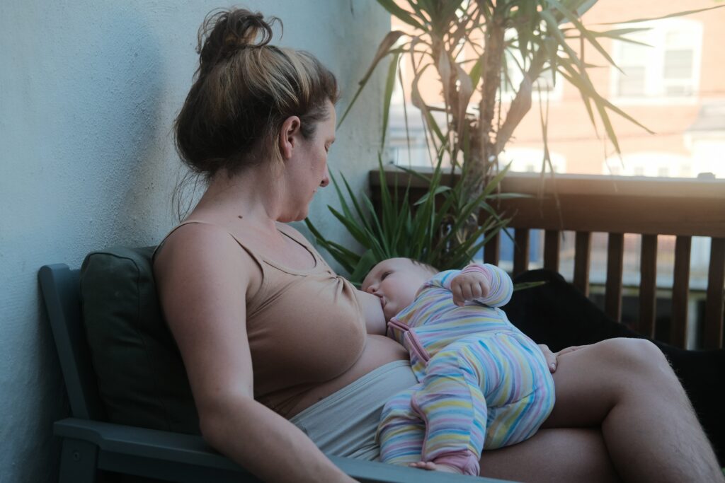 Mulher amamentando bebê em uma varanda.